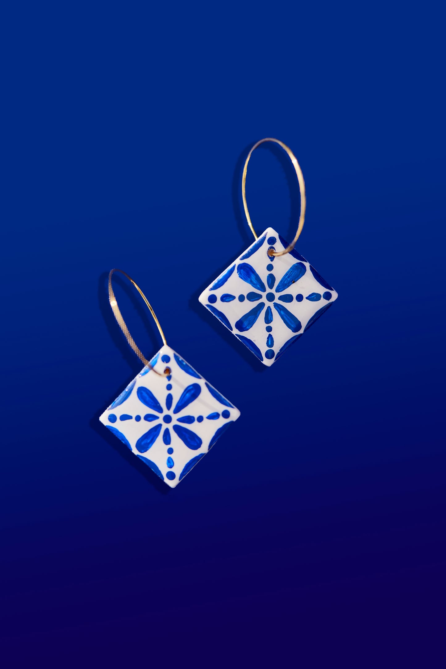 Hechos de arcilla polimérica, muy ligera para una comodidad excepcional.
Pintados a mano con detalles en azul vibrante.
Diseño colgante con engarces bañados en oro.
