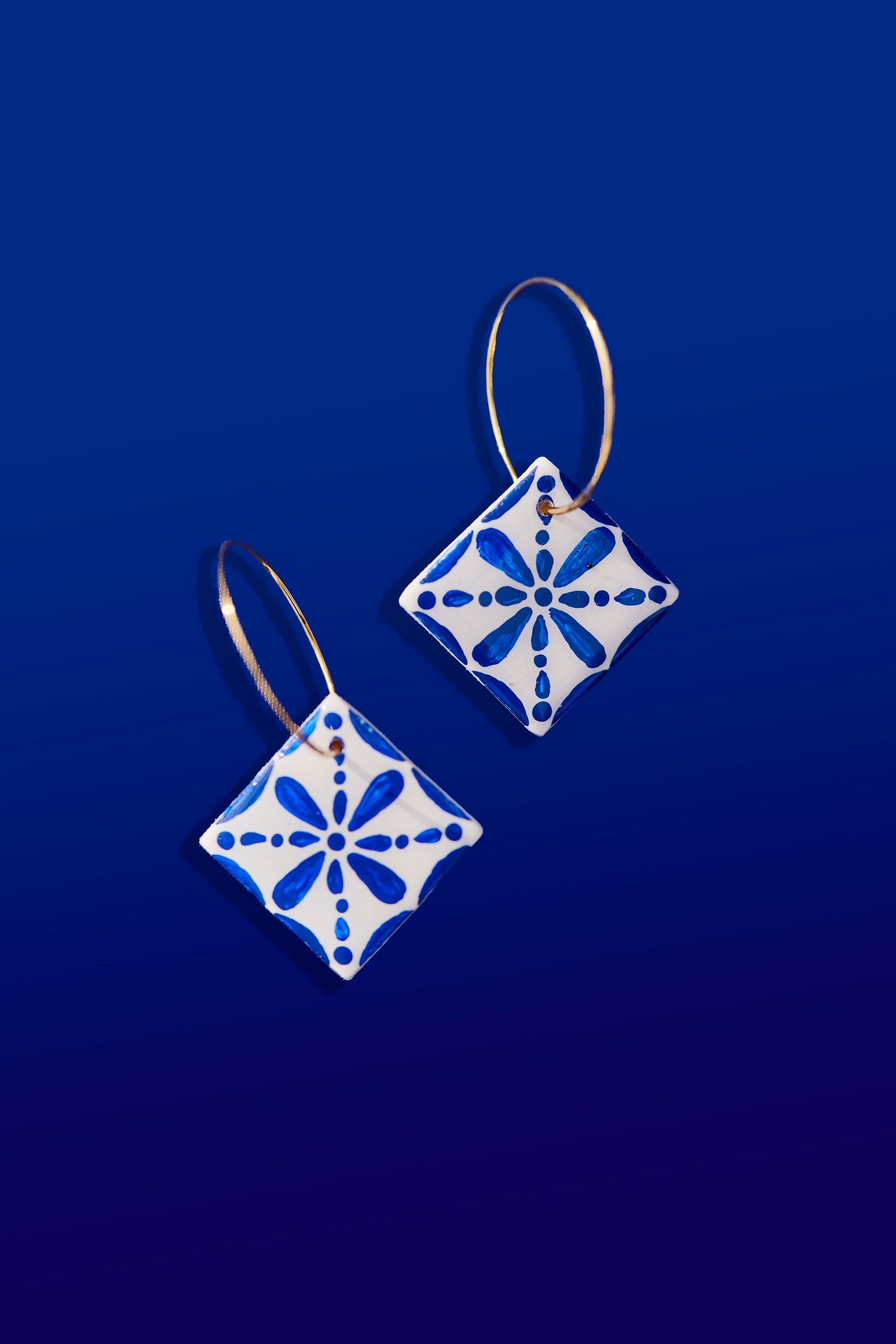 Hechos de arcilla polimérica, muy ligera para una comodidad excepcional.
Pintados a mano con detalles en azul vibrante.
Diseño colgante con engarces bañados en oro.
